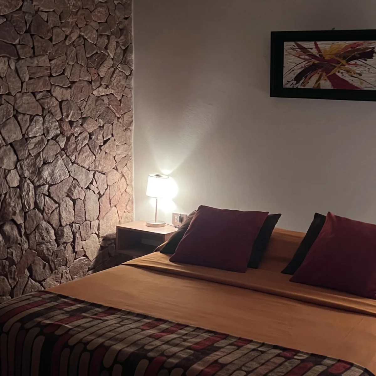 dormitorio de suite en Chilecito con pared de piedra y sommier queen en Refugio