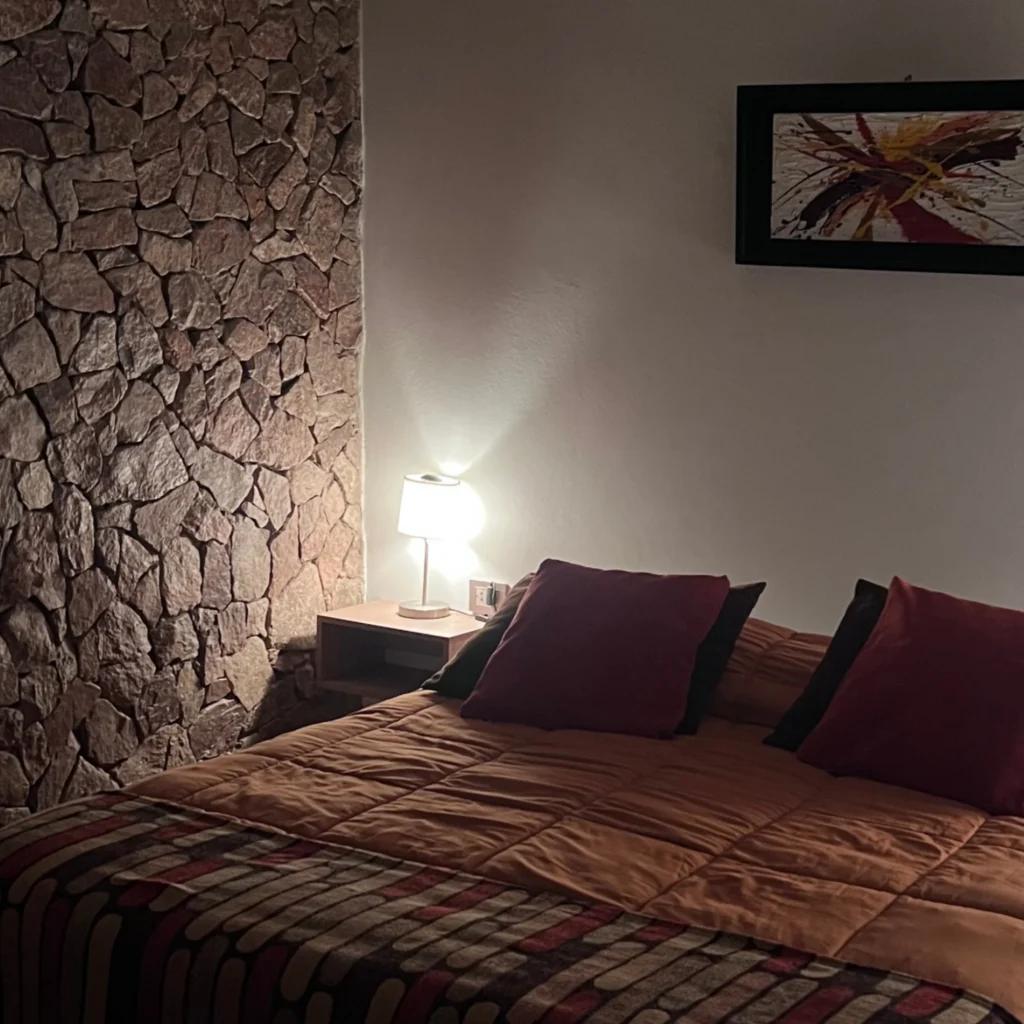 dormitorio de suite en Chilecito con pared de piedra y cama queen en Refugio